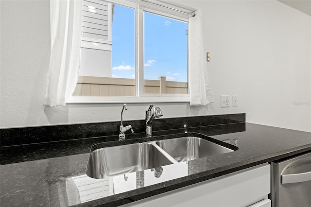 kitchen featuring dark stone countertops, dishwasher, and sink