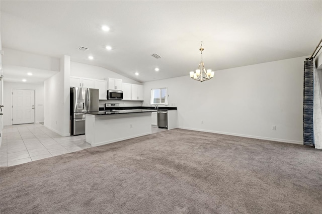 kitchen with stainless steel appliances, decorative light fixtures, light colored carpet, white cabinets, and a center island