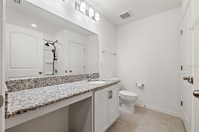 bathroom featuring toilet, vanity, walk in shower, and tile patterned flooring