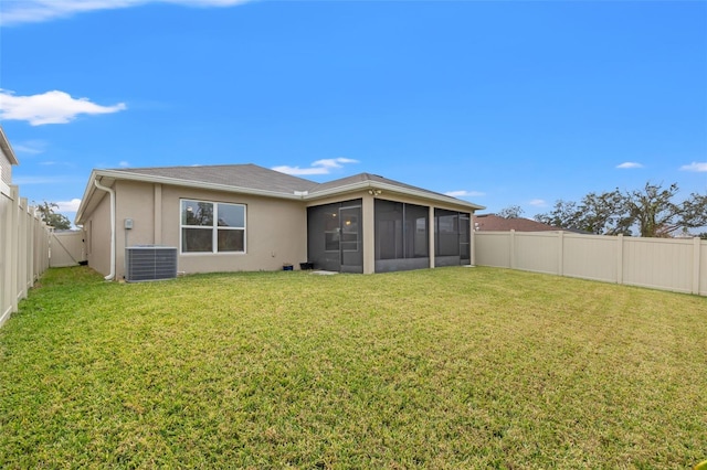 rear view of property with cooling unit, a sunroom, and a lawn