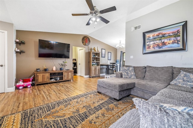 living room with hardwood / wood-style flooring, ceiling fan with notable chandelier, and lofted ceiling