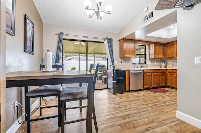 kitchen featuring dishwasher, a textured ceiling, a chandelier, and light hardwood / wood-style floors