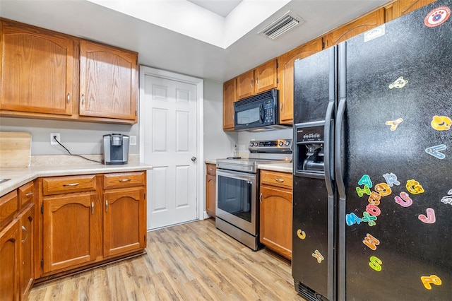 kitchen with black appliances and light hardwood / wood-style flooring