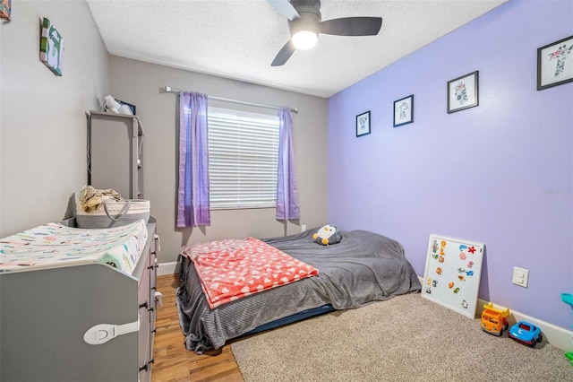 bedroom with hardwood / wood-style floors, ceiling fan, and a textured ceiling