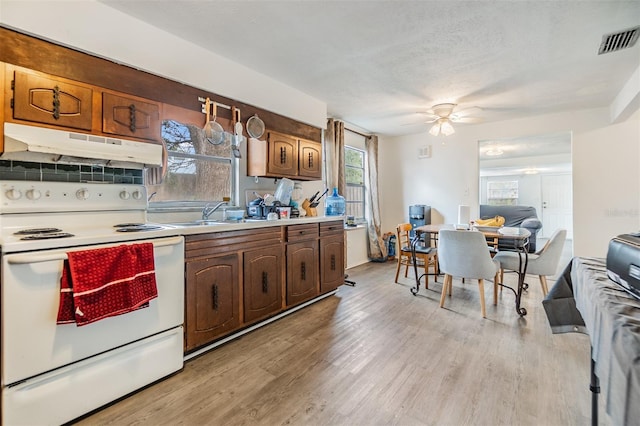 kitchen with electric stove, sink, light hardwood / wood-style flooring, ceiling fan, and tasteful backsplash