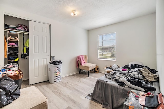 bedroom featuring a textured ceiling, light wood-type flooring, and a closet