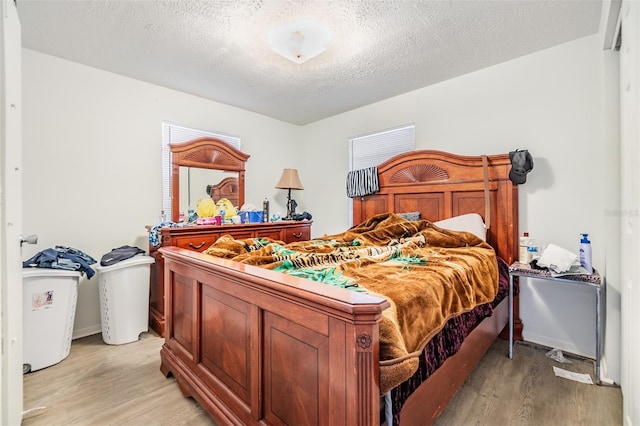 bedroom with a textured ceiling and light wood-type flooring