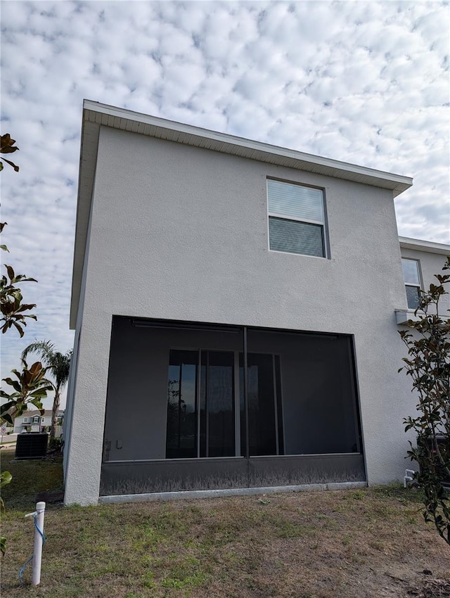 rear view of property featuring a lawn, a sunroom, and central air condition unit