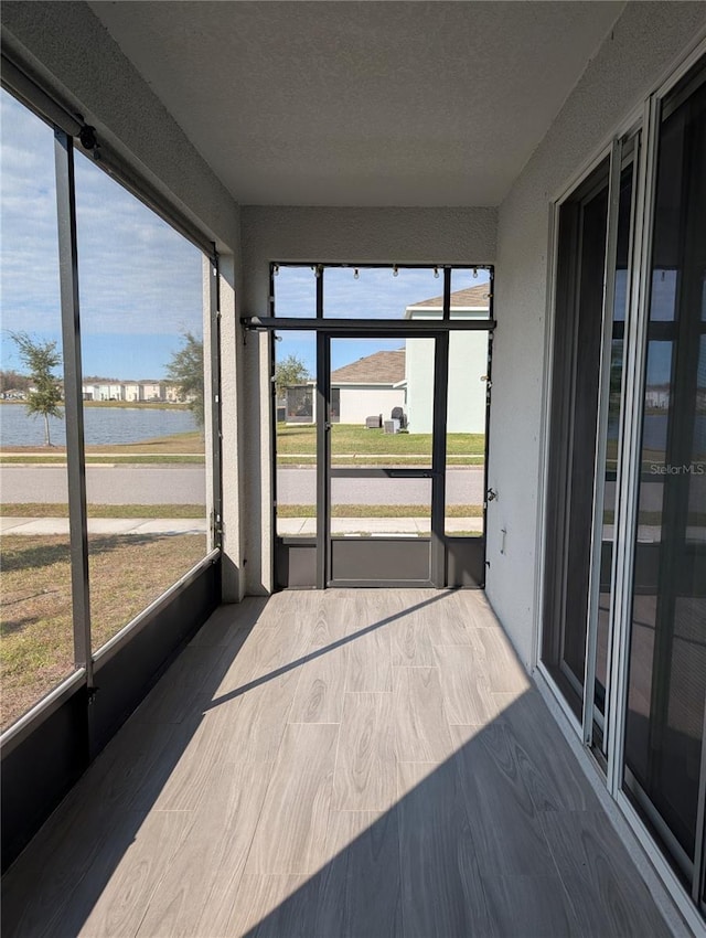 unfurnished sunroom featuring a water view