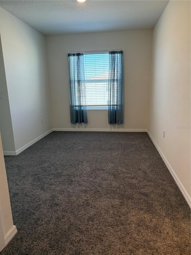 unfurnished room with dark colored carpet