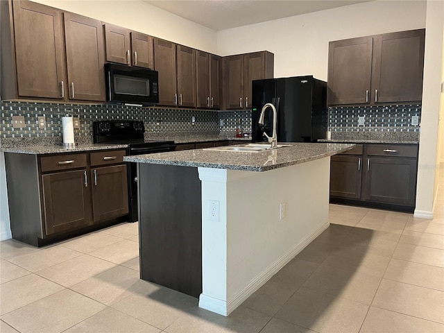 kitchen featuring dark brown cabinetry, sink, black appliances, and a center island with sink