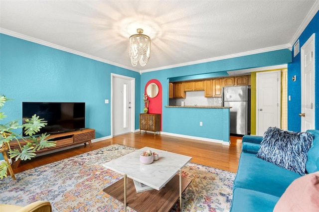 living room with light hardwood / wood-style floors, crown molding, and a notable chandelier