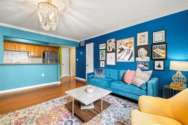 living room featuring wood-type flooring, crown molding, and a notable chandelier