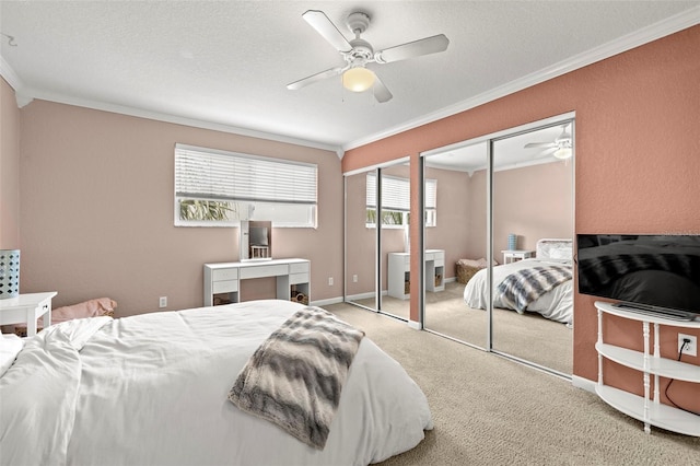 carpeted bedroom featuring ceiling fan, crown molding, a textured ceiling, and two closets