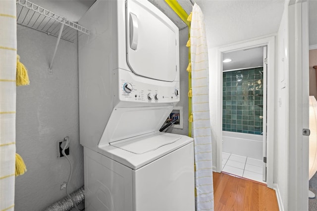 washroom with hardwood / wood-style flooring and stacked washer / drying machine