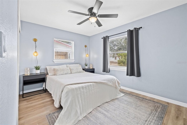 bedroom with light wood-type flooring, ceiling fan, and multiple windows