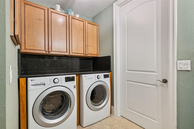 washroom with cabinet space, light tile patterned flooring, separate washer and dryer, and a textured wall