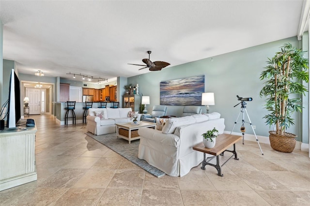 living area featuring track lighting, a ceiling fan, and baseboards