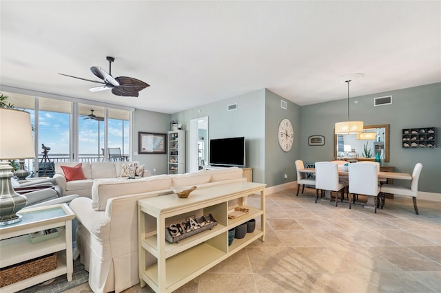 living area with visible vents, a ceiling fan, and baseboards