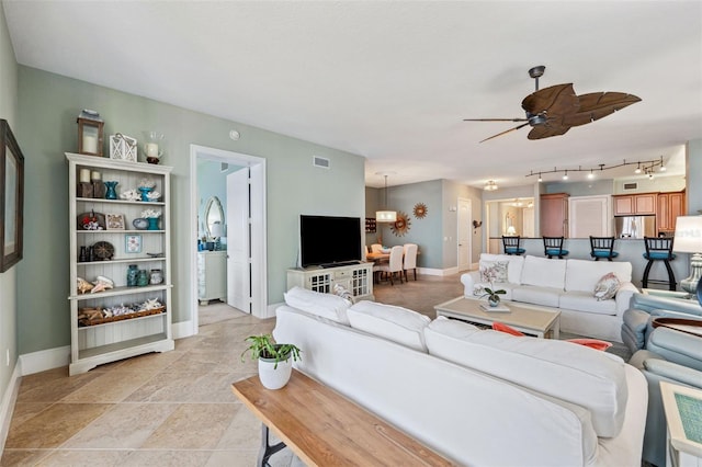 living area with baseboards, visible vents, and a ceiling fan