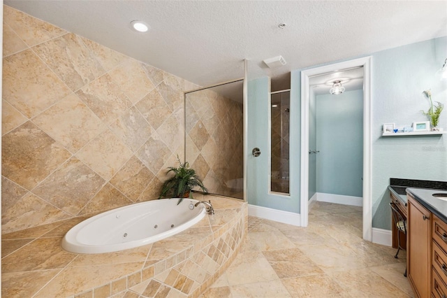 bathroom with a stall shower, vanity, a textured ceiling, baseboards, and a tub with jets