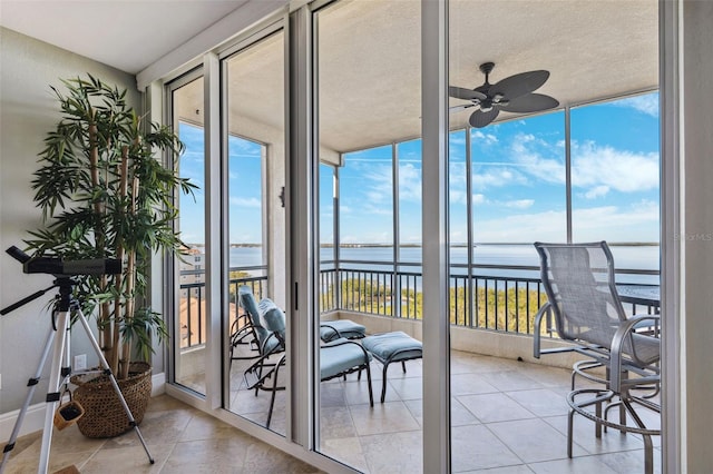 sunroom / solarium featuring ceiling fan and a water view