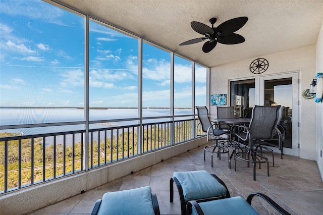 sunroom / solarium with ceiling fan and a water view