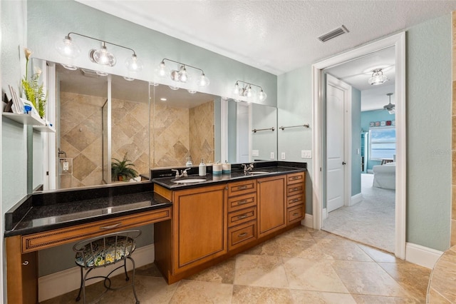 full bath featuring visible vents, a sink, a textured ceiling, and double vanity