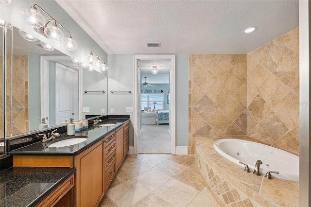 ensuite bathroom with visible vents, a sink, a textured ceiling, and a tub with jets