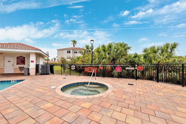 view of swimming pool featuring a patio area, fence, and a hot tub