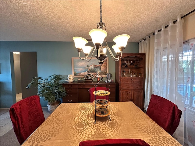 dining area featuring a chandelier, a textured ceiling, and tile patterned floors