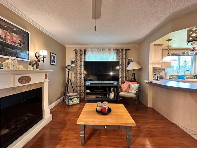 living room featuring a fireplace, dark hardwood / wood-style flooring, a textured ceiling, and crown molding