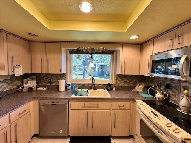 kitchen featuring a raised ceiling, sink, light tile patterned floors, and stainless steel appliances