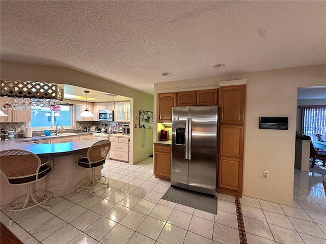 kitchen featuring sink, backsplash, decorative light fixtures, light tile patterned floors, and appliances with stainless steel finishes