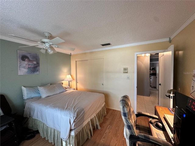 bedroom featuring a textured ceiling, light hardwood / wood-style flooring, ceiling fan, and crown molding