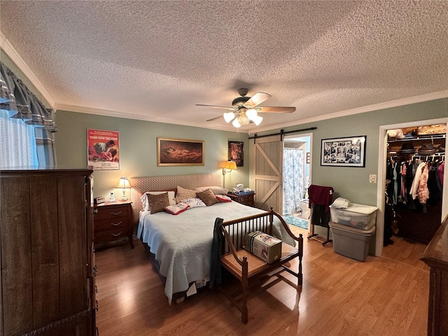 bedroom with a barn door, ceiling fan, and ornamental molding