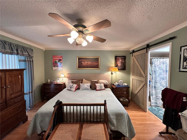 bedroom featuring ceiling fan, a barn door, crown molding, access to outside, and light wood-type flooring