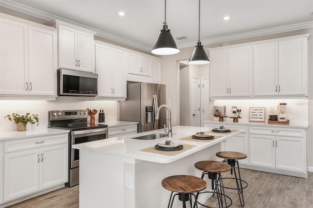 kitchen with white cabinets, sink, stainless steel appliances, and a kitchen island with sink