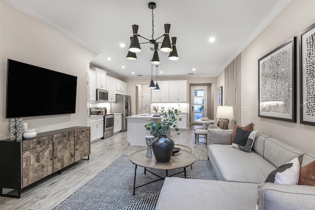 living room with sink, light hardwood / wood-style flooring, a chandelier, and ornamental molding