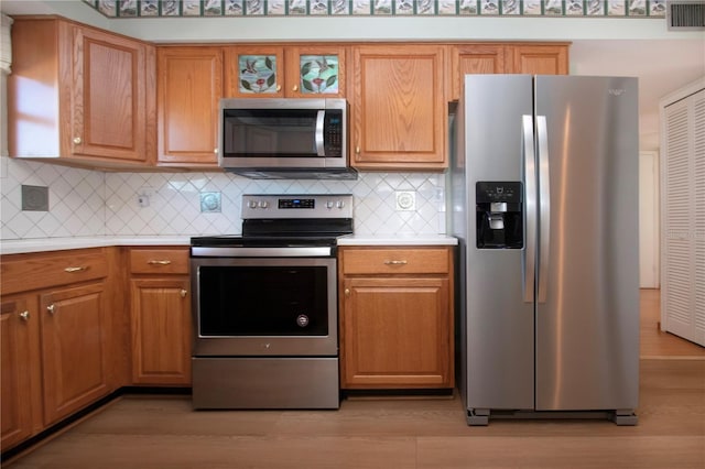 kitchen featuring decorative backsplash, light wood-type flooring, and appliances with stainless steel finishes