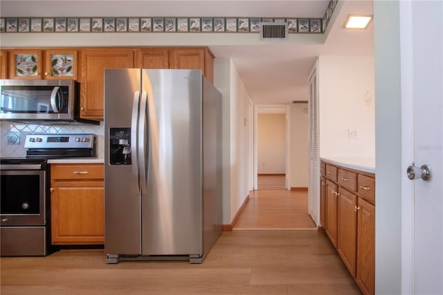 kitchen with stainless steel appliances, tasteful backsplash, and light wood-type flooring