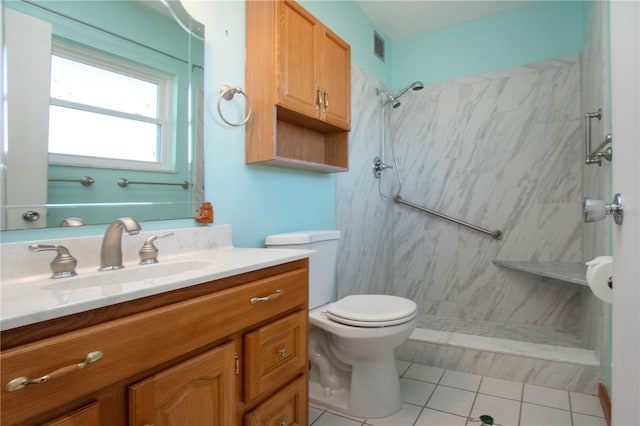 bathroom with a tile shower, vanity, tile patterned flooring, and toilet