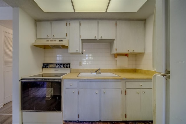 kitchen featuring white appliances, decorative backsplash, light wood-type flooring, white cabinets, and sink