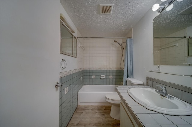 full bathroom featuring a textured ceiling, toilet, wood-type flooring, shower / bath combo, and vanity