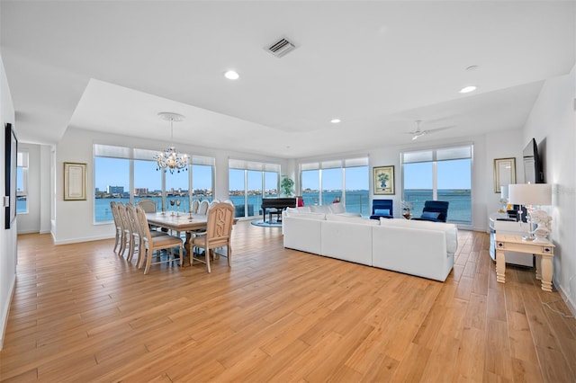 living room featuring ceiling fan with notable chandelier and light wood-type flooring