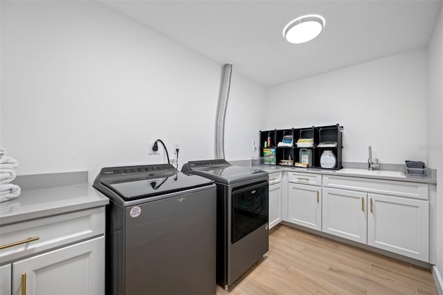 laundry room with cabinets, separate washer and dryer, and sink