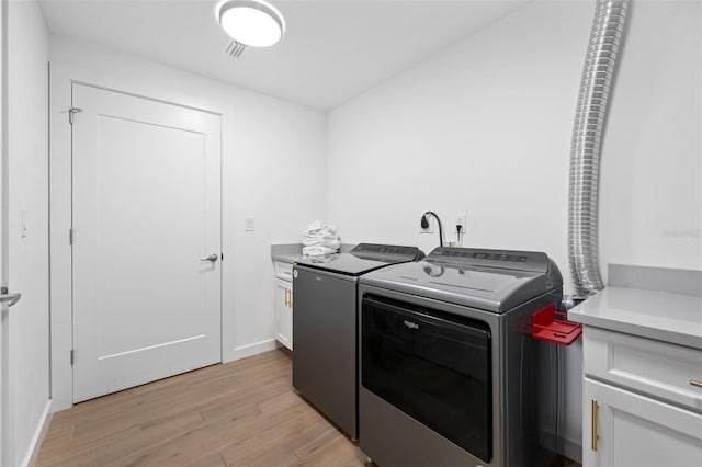 laundry room with light wood-type flooring, cabinets, and separate washer and dryer