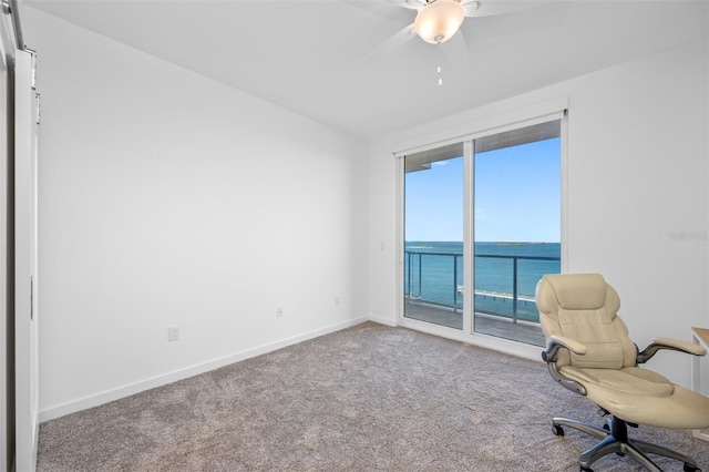 unfurnished office with a water view, ceiling fan, and carpet flooring