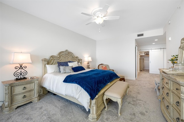 carpeted bedroom featuring ceiling fan and a barn door