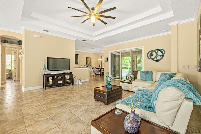 living room with a raised ceiling, ceiling fan, and light tile patterned floors